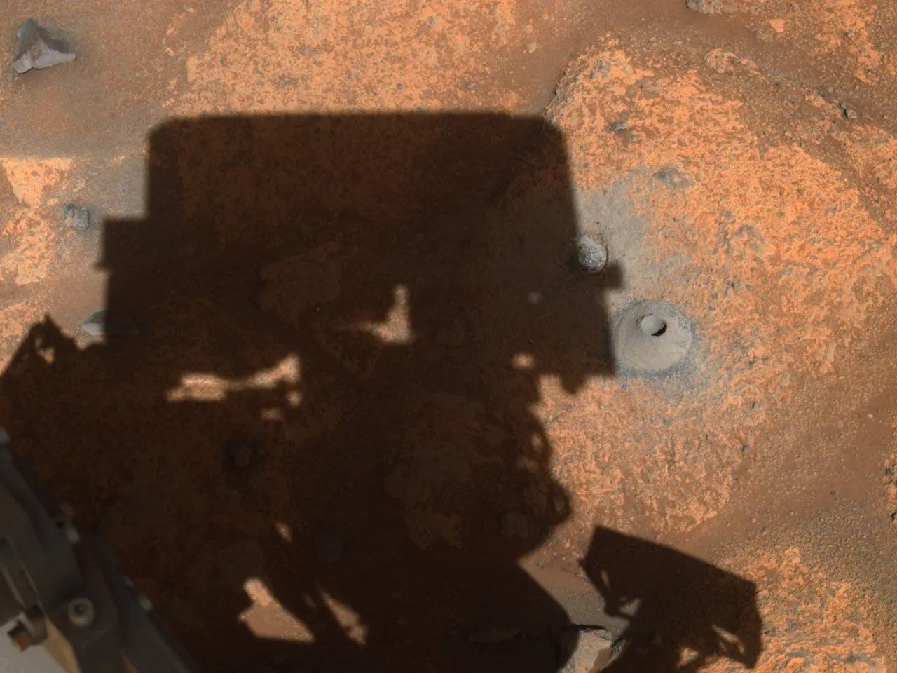 Perseverance's Navigation Camera Image of First Borehole: The drill hole from Perseverance’s first sample-collection attempt can be seen, along with the shadow of the rover, in this image taken by one of the rover’s navigation cameras. Credits: NASA/JPL-Caltech.